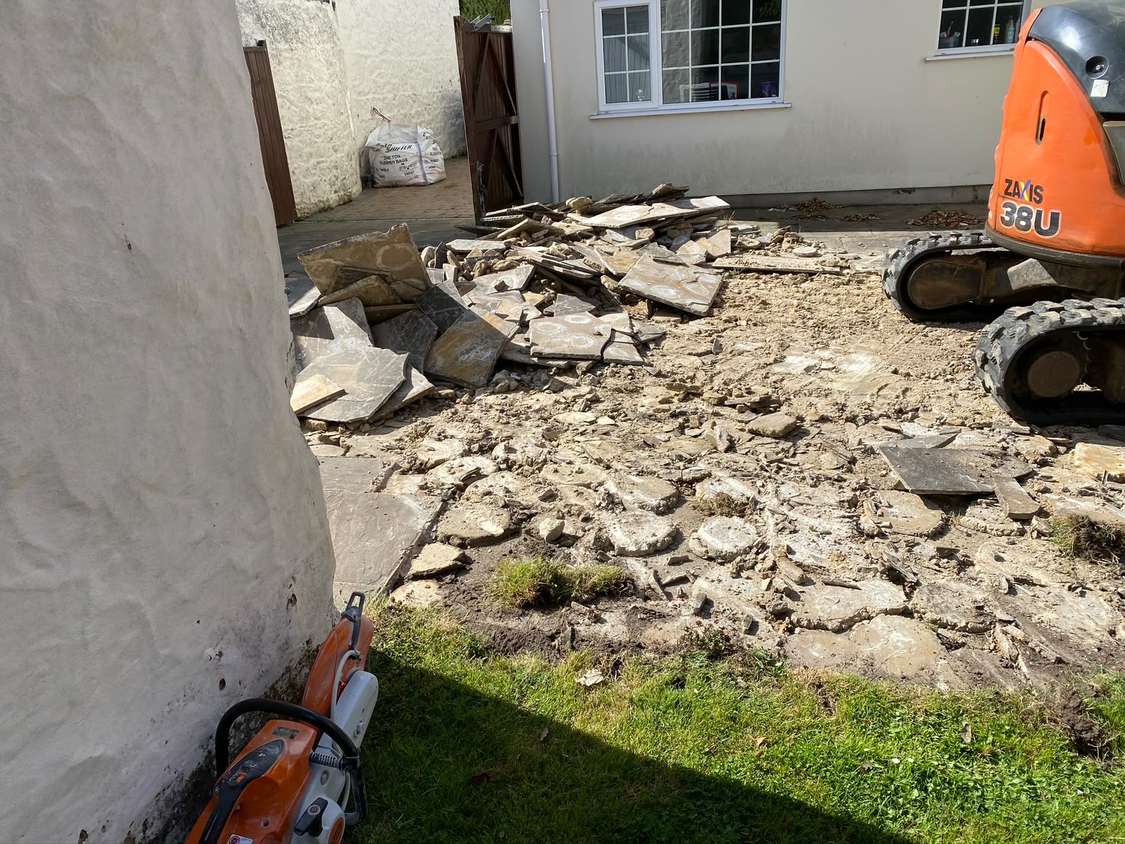 Existing patio slabs broken out and stacked for removal
