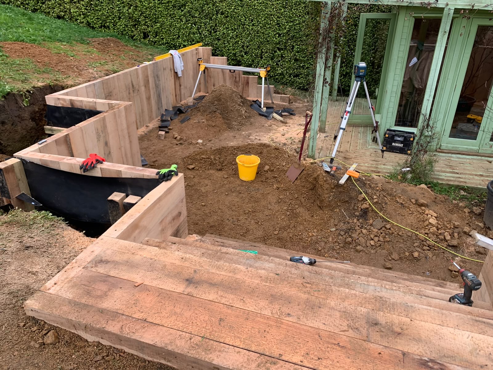 Sleeper retaining walls lined with membrane before backfilling