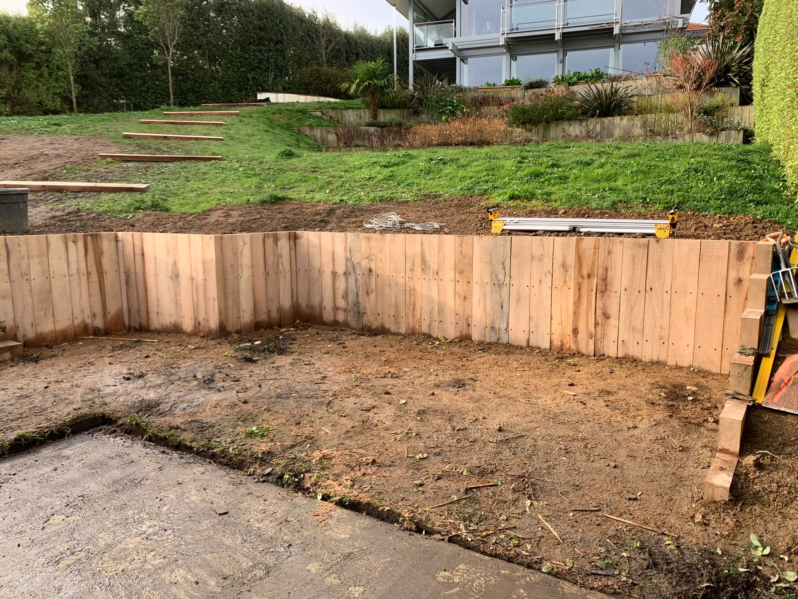 Vertical sleeper retaining wall built to hold the higher bank