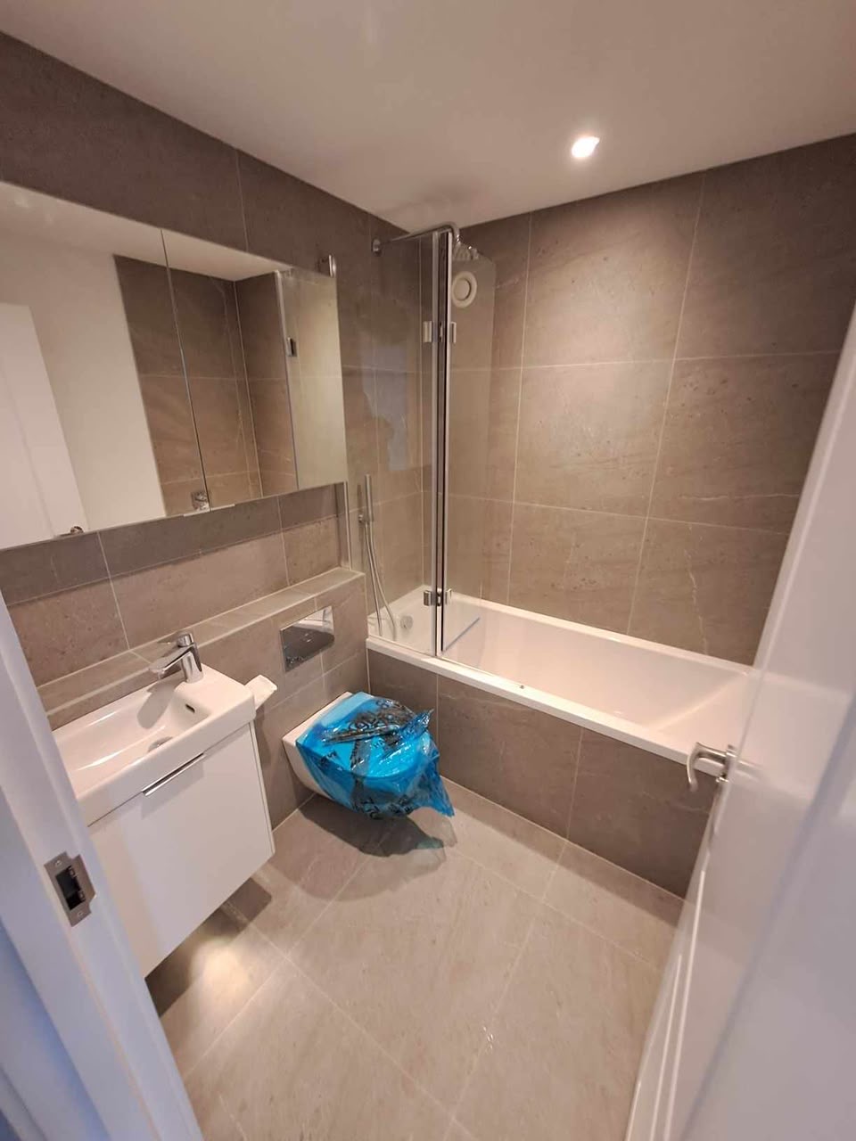 Completed bathroom with bath, screen and full-height tiling
