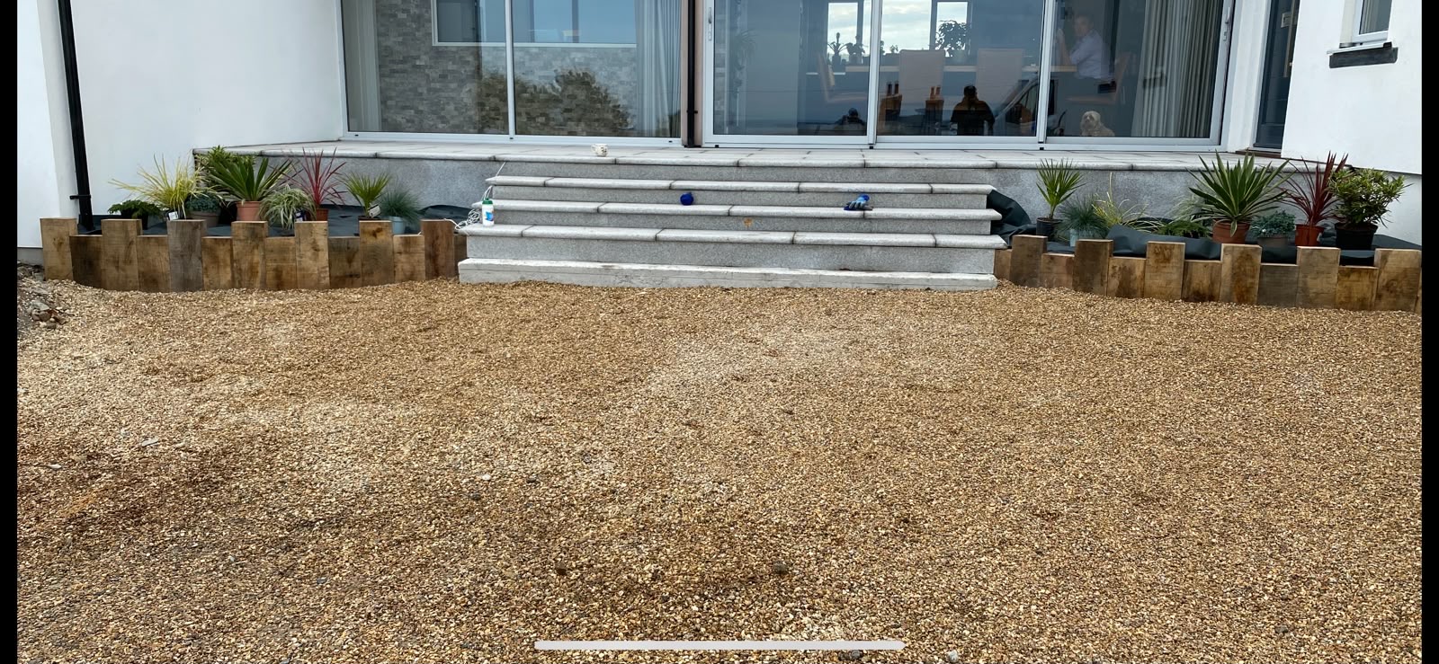 Granite steps down to the gravel area with oak sleeper planter edging