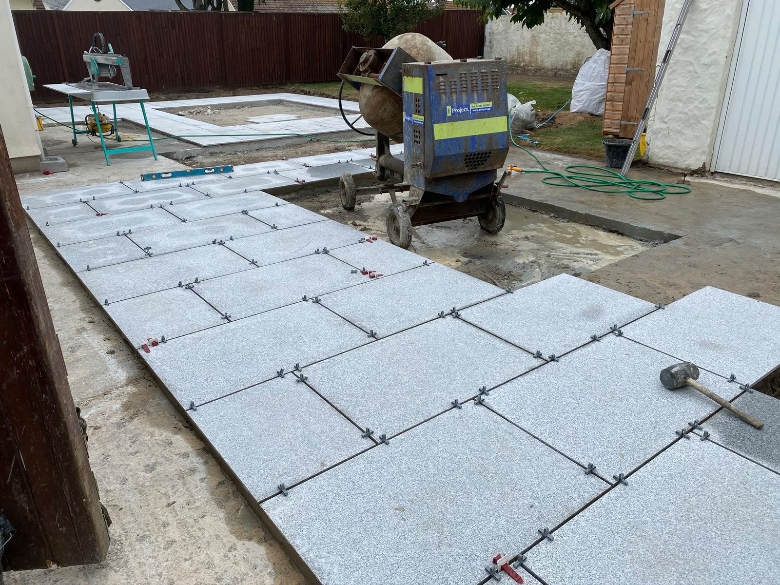 Large-format grey granite slabs being laid on a full concrete bed, Guernsey