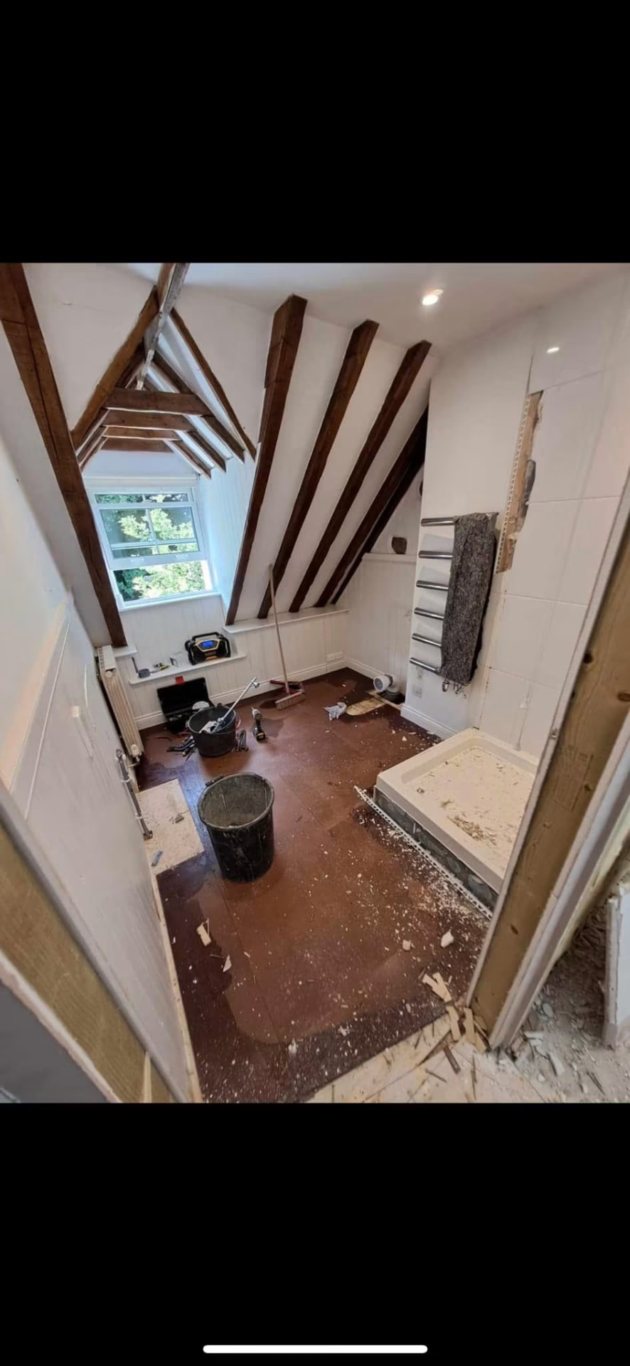 The original loft bathroom being stripped out beneath the exposed timber beams